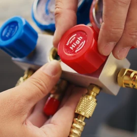 Person adjusting refrigeration gauge knobs